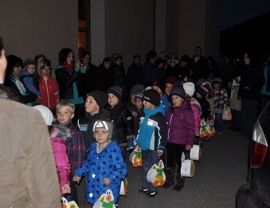 Eine Gruppe von Kindern und Erwachsenen versammelt sich draußen bei Nacht und hält Taschen. Einige machen Fotos.
