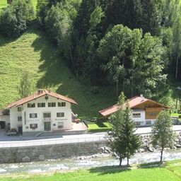 Eine Luftaufnahme eines Gästehauses mit rotem Dach, umgeben von üppigen grünen Hügeln und einem fließenden Fluss.