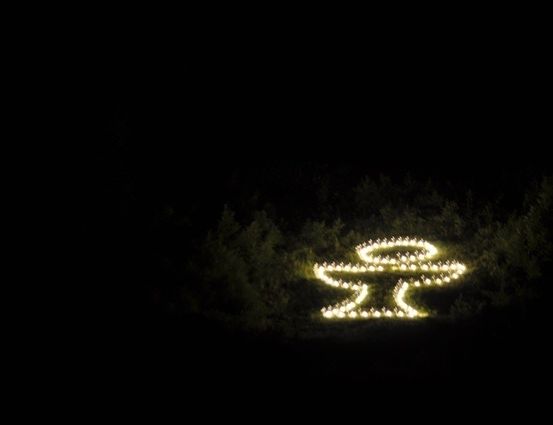 Eine kreisförmige Lichtanzeige, die einer Sonne oder einem stilisierten Symbol ähnelt, ist vor einem dunklen Hintergrund beleuchtet.