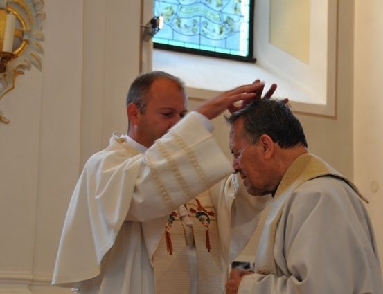Ein Priester legt während einer religiösen Zeremonie in einer Kirche seine Hände auf den Kopf eines anderen Priesters.