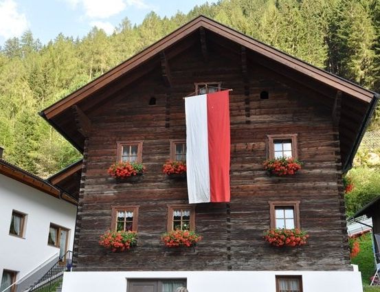 Ein Holzhaus mit einer Flagge und Blumenkästen an einem sonnigen Tag.