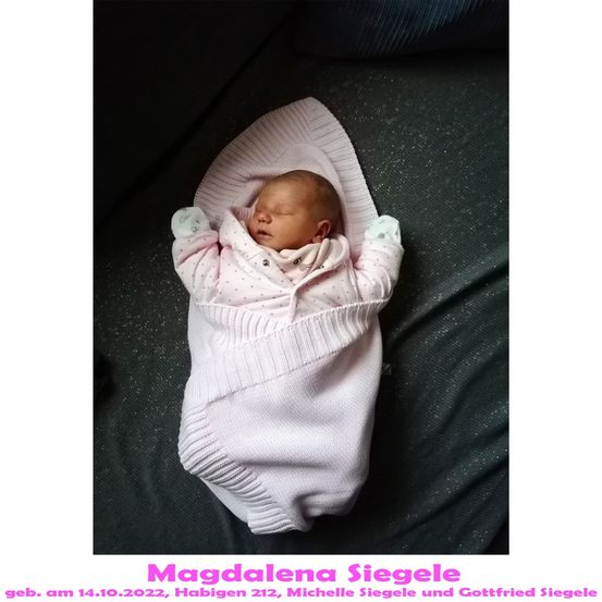Ein neugeborenes Babymädchen, eingewickelt in eine rosa Strickdecke, schläft auf einem dunklen Hintergrund. Das Baby trägt ein rosa gepunktetes Outfit. Das Bild hat einen Wasserzeichen mit dem Text 'Magdalena Siegele' und dem Datum '14.10.2022'.