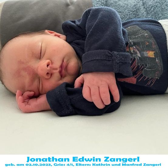 Ein Babyjunge namens Jonathan Edwin Zangerl, geboren am 10. Februar 2023, schläft friedlich auf einem Bett mit einer blauen Decke. Er trägt ein blaues Langarmshirt mit einem grafischen Design.
