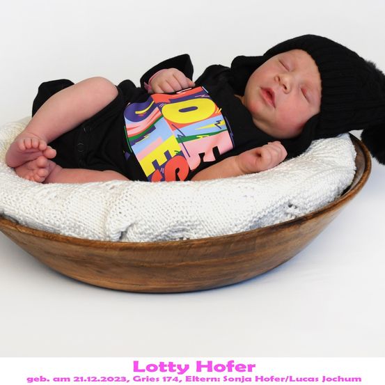Ein schlafendes Baby in einem bunten T-Shirt und einer schwarzen Mütze ruht in einer mit weißer Stoff ausgekleideten Holzschüssel, aufgenommen am 21. Dezember 2023.