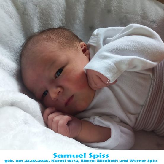 Ein Neugeborenes namens Samuel Spiss, geboren am 23. Oktober 2023, liegt auf einer weißen Decke und lächelt in die Kamera.