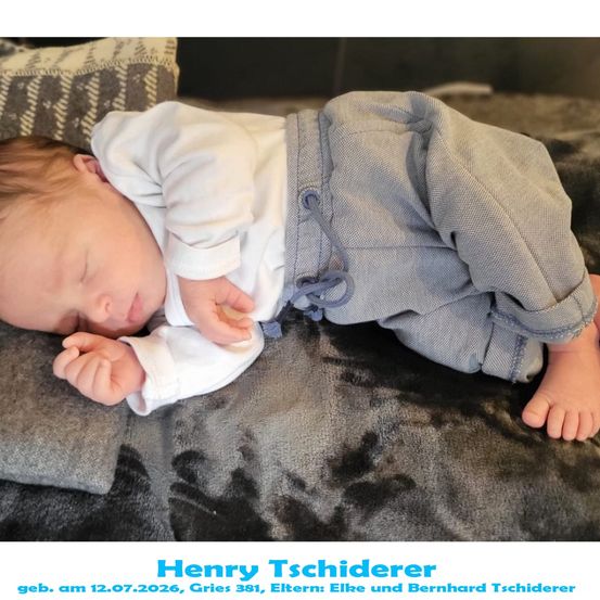 Ein schlafender Babyjunge, Henry Tschiderer, geboren am 12.07.2026, liegt auf einer Decke mit gefalteten Händen. Er trägt ein weißes Hemd und graue Hosen.