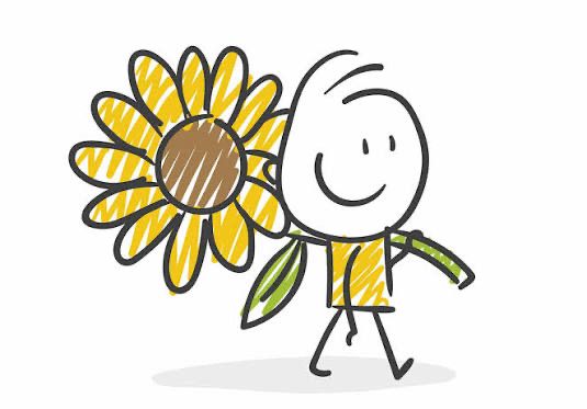A person holding a sunflower, smiling and looking at it with a joyful expression.