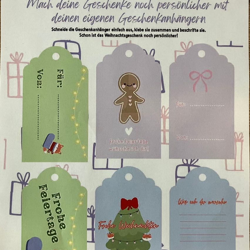 A white sheet with various gift tags, each with unique designs and messages. One tag says 'Frohe Feiertage', another 'Frohe Weihnachtswünsche', and others have simple phrases and illustrations.