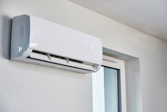 Eine weiße Klimaanlage ist an einer Wand neben einem Glasfenster montiert.