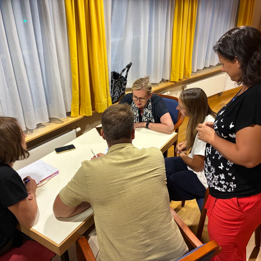 Diskussion im Büro: Vier Personen sitzen an einem Tisch und besprechen Unterlagen.