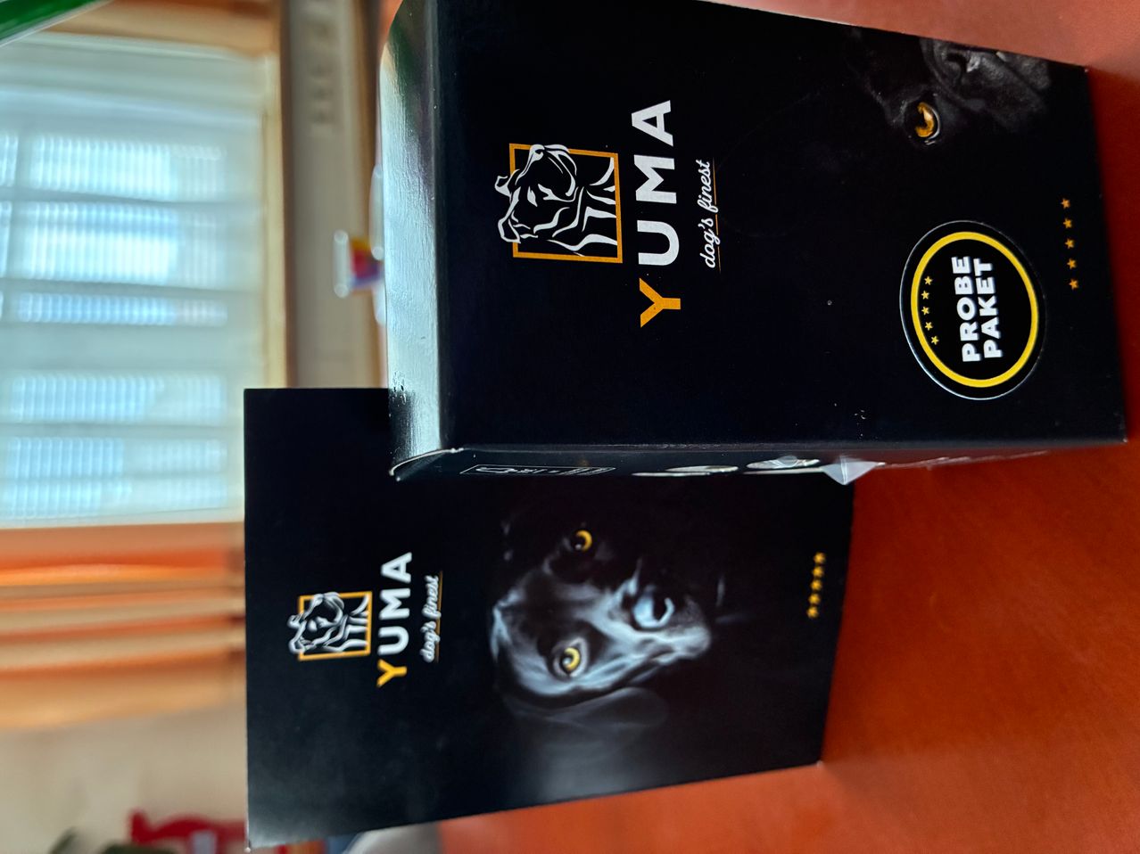 Two black boxes with the label YUMA on them. The box on top has a cat's picture and a yellow circle with stars. The box below has a dog's picture.
