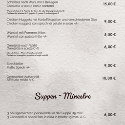 Das Menü bietet verschiedene Auswahlmöglichkeiten wie Wienerschnitzel, Chicken Nuggets, Würste, Omelette und verschiedene Beilagen. Die Suppe enthält hausgemachte Speckknödel. Die Preise sind in Euro angegeben.