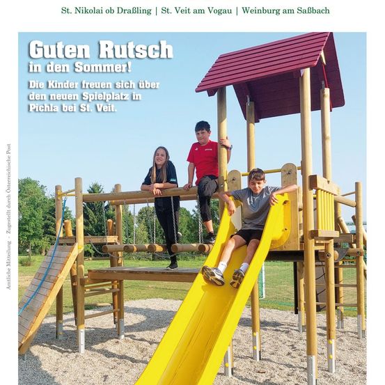 Drei Kinder spielen auf einem hölzernen Spielplatz mit rotem Dach. Zwei Jungen rutschen auf einer gelben Rutsche, während ein Mädchen daneben steht. Dahinter hängt eine Schaukel an einer Holzkonstruktion. Der Bereich ist mit Kies bedeckt und von Bäumen umgeben.