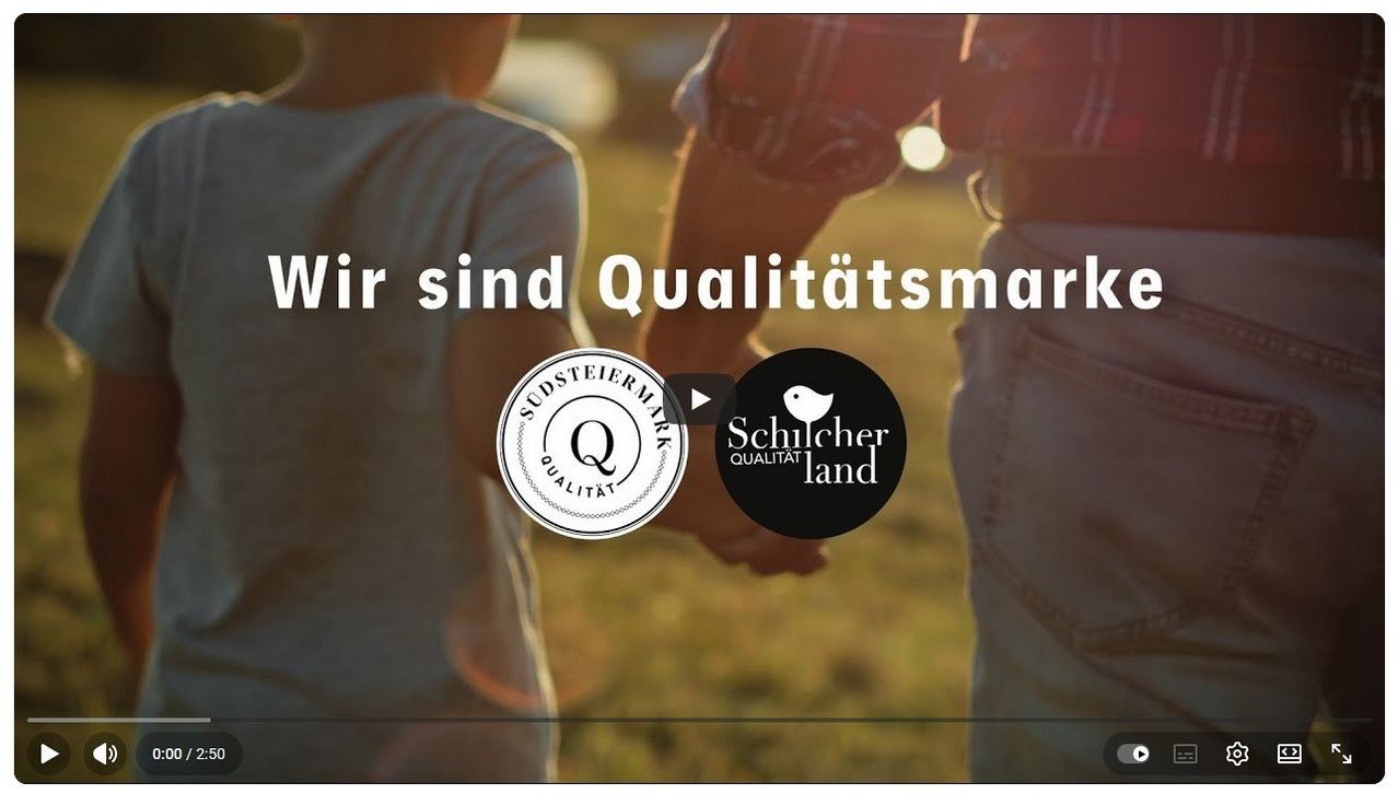 Eine Outdoor-Szene mit zwei Kindern, die Händchen halten, eines in Weiß und das andere in Grau. Die Worte 'Wir sind Qualitätsmark' und ein Logo sind zu sehen.