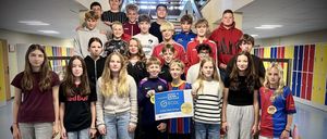 Eine Gruppe von Teenagern und jungen Erwachsenen steht auf einer Treppe, lächelt und posiert für ein Foto. Eine Person hält ein blaues Banner mit dem Text ECDL und einem Logo.