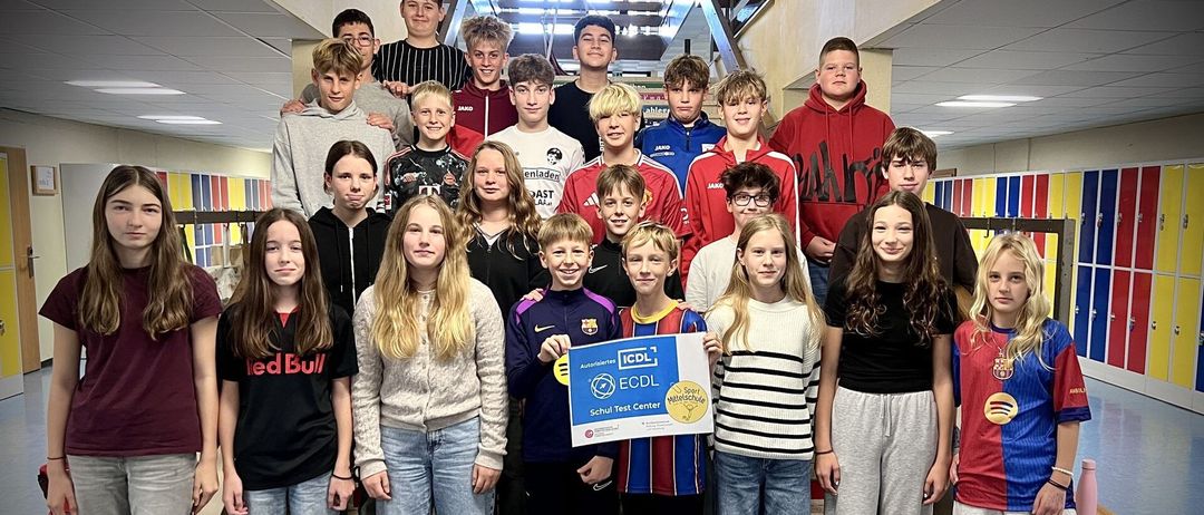 Eine Gruppe von Teenagern und jungen Erwachsenen steht auf einer Treppe, lächelt und posiert für ein Foto. Eine Person hält ein blaues Banner mit dem Text ECDL und einem Logo.