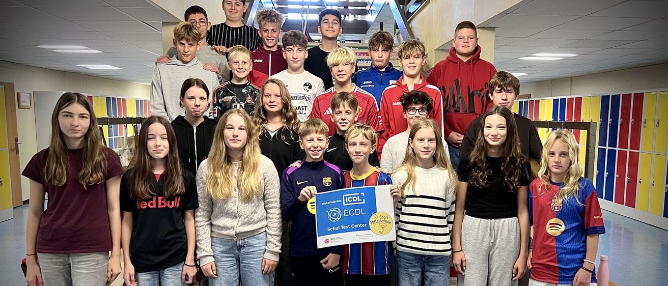 Eine Gruppe von Teenagern und jungen Erwachsenen steht auf einer Treppe, lächelt und posiert für ein Foto. Eine Person hält ein blaues Banner mit dem Text ECDL und einem Logo.