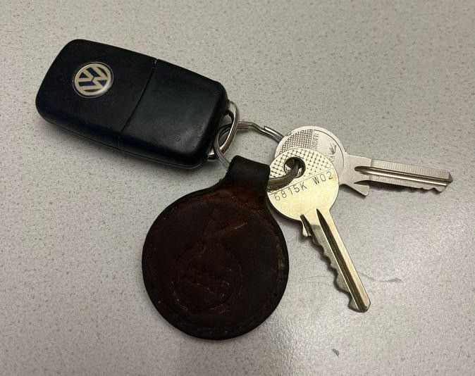 Ein schwarzer Volkswagen-Autoschlüssel mit einem Metallschlüssel, auf einer grauen Oberfläche.