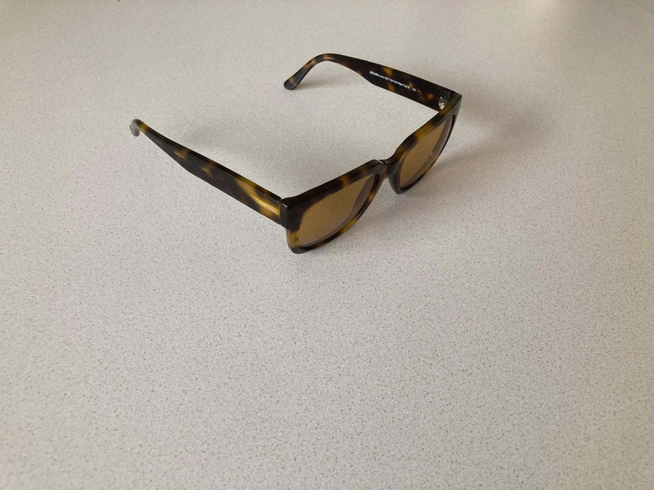 Ein Paar rechteckiger Sonnenbrille mit braunen Gläsern und einer Schildpatt-Musterung auf einer weißen Oberfläche.