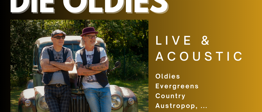Zwei Männer stehen neben einem Oldtimer. Einer trägt Hut und Brille, der andere ein kariertes Hemd. Sie lächeln, möglicherweise für ein Foto. Dahinter befindet sich eine Rasenfläche mit Bäumen.