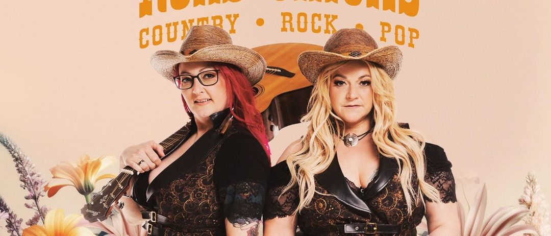 Zwei Frauen in Cowboyhüten und Kleidern stehen vor einem rosa Hintergrund mit Blumen. Eine hält eine Gitarre, die andere eine gelbe Gitarre. 'Road Chicks' und 'Country Rock Pop' sind über ihnen geschrieben.