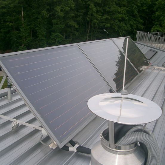 Ein Solarpanel ist auf dem Dach montiert, mit einer silberfarbenen Struktur, möglicherweise ein Solarwarmwasserbereiter, der daran befestigt ist.