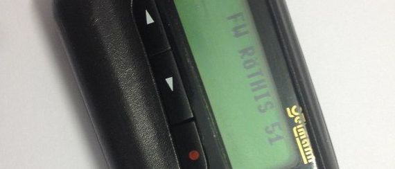 Ein schwarzes elektronisches Geraet mit einem gruenen Bildschirm zeigt den Text 'FM OUTPUTS 51'. Es hat Tasten zur Navigation und Energieversorgung.