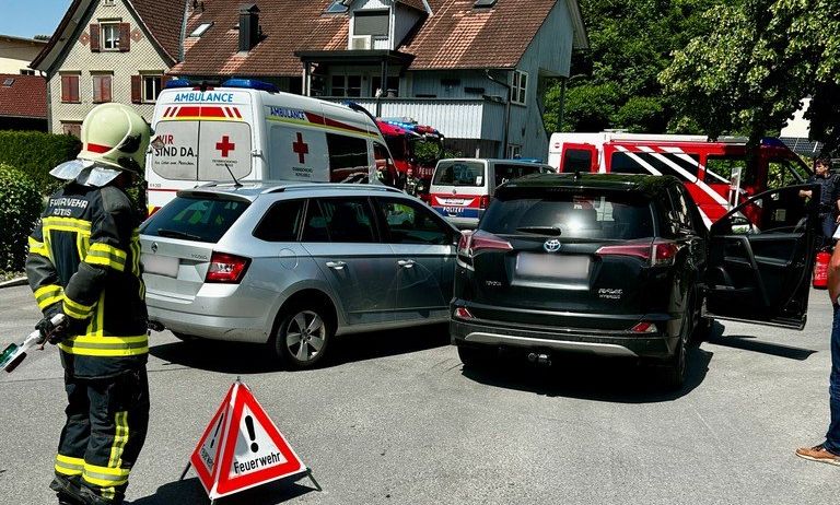 Ein Feuerwehrmann steht neben einem Feuerwehrwagen und einem Krankenwagen am Straßenrand mit zwei beschädigten Autos.