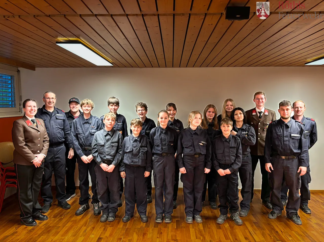 Eine Gruppe von Menschen in Uniformen posiert für ein Foto in einem Raum mit Holzboden.