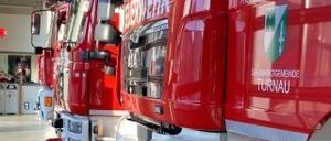 Eine Reihe roter Feuerwehrfahrzeuge in einer Garage geparkt, jedes mit einem Logo und dem Wort Turnau an der Seite.