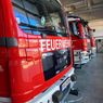Eine Reihe roter Feuerwehrfahrzeuge steht in einer Garage. Auf den Fahrzeugen steht das Wort Feuerwehr geschrieben.