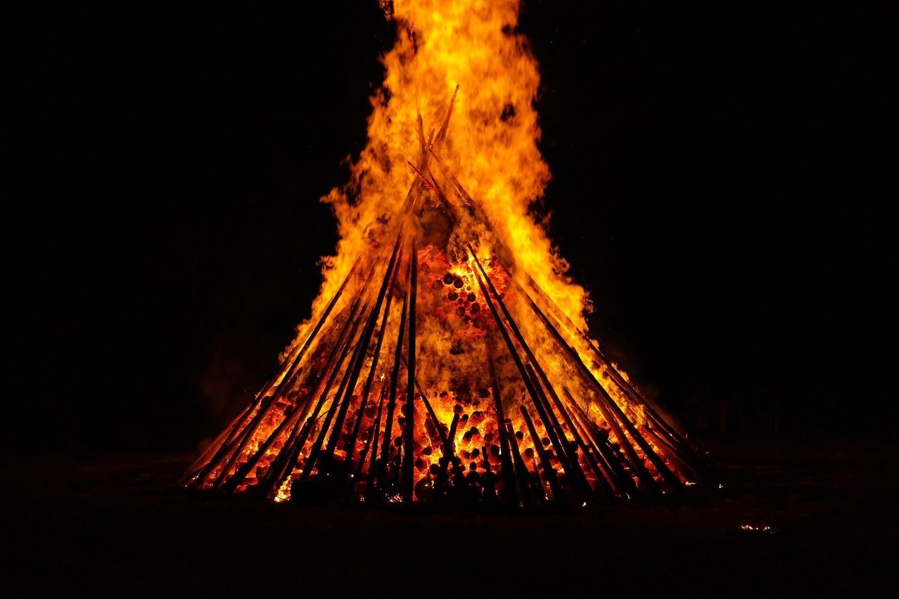 Ein großes Lagerfeuer, beleuchtet von seinen eigenen intensiven Flammen, brennt in der dunklen Nacht.
