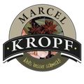 Marcel Kropf Logo mit einer Mischung aus Gewürzen und Kräutern und dem Slogan 'Weil's besser schmeckt!' in grünen Buchstaben.