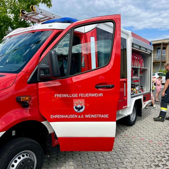 Ein roter Feuerwehrwagen mit der Aufschrift Freiwillige Feuerwehr Ehrenhausen a.d. Weinstraße, geparkt auf einer Kopfsteinpflasterstraße mit einer Leiter obenauf.