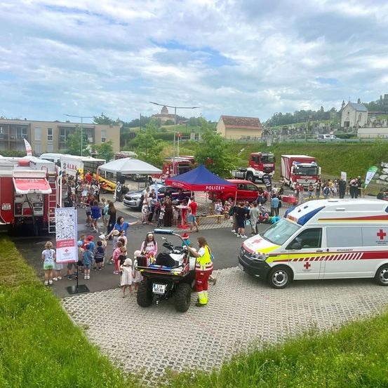 Eine Gemeinschaftsveranstaltung mit mehreren Rettungsfahrzeugen, einer Menschenmenge und einer Person auf einem ATV in der Nähe eines weißen Krankenwagens.