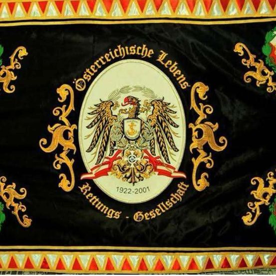 Ein schwarzer Banner mit einem goldenen Emblem, das zwei Adler zeigt, die einen Schild halten, umgeben von dekorativen Elementen und Text in Deutsch.