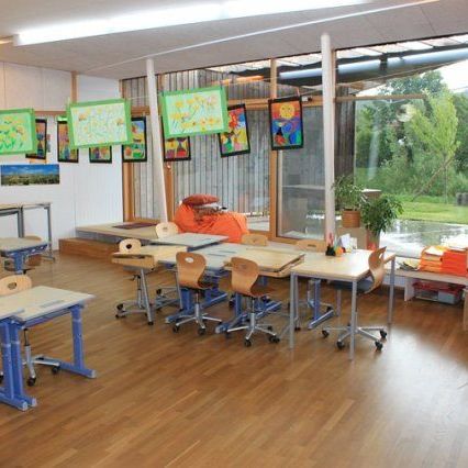 Bild enthält, Architecture, Building, School, Classroom, Indoors, Room, Wood, Chair, Furniture, Person