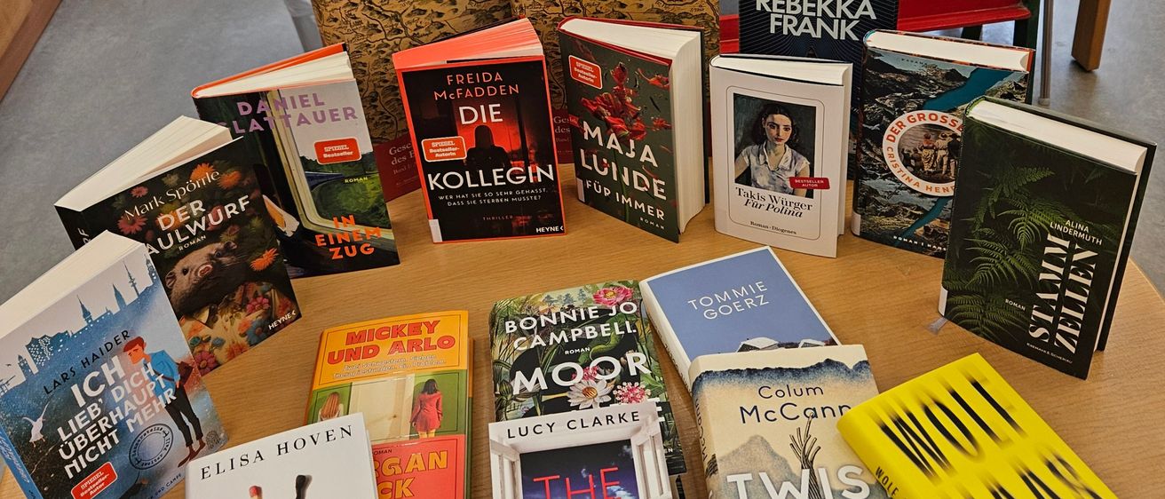 Ein Tisch mit einem schwarzen Brett dahinter, auf dem steht 'Heute ist ein guter Tag zum Lesen'. Viele Bücher sind auf dem Tisch ausgestellt, darunter einige Romane und Kochbücher.