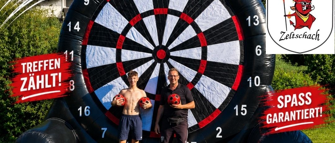 Zwei Männer stehen vor einem großen aufblasbaren Dartboard mit einem Fußball und einem Dart im Hintergrund. Der Text lautet 'All Dar' und 'Treffen Zahlt! 8'. Das Datum ist 12.09.2026 und der Ort ist Waldstadion Zeltschach.