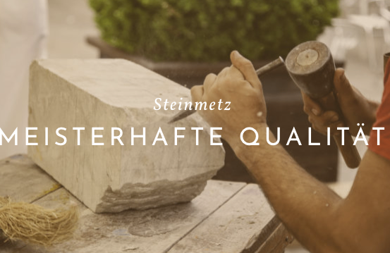 Eine Person schnitzelt einen Stein auf einem Holztisch mit Werkzeugen. Der Stein ist weiß. Der Text 'Steinmetz' und 'MEISTERHAFTE QUALITAT' ist auf dem Bild geschrieben.