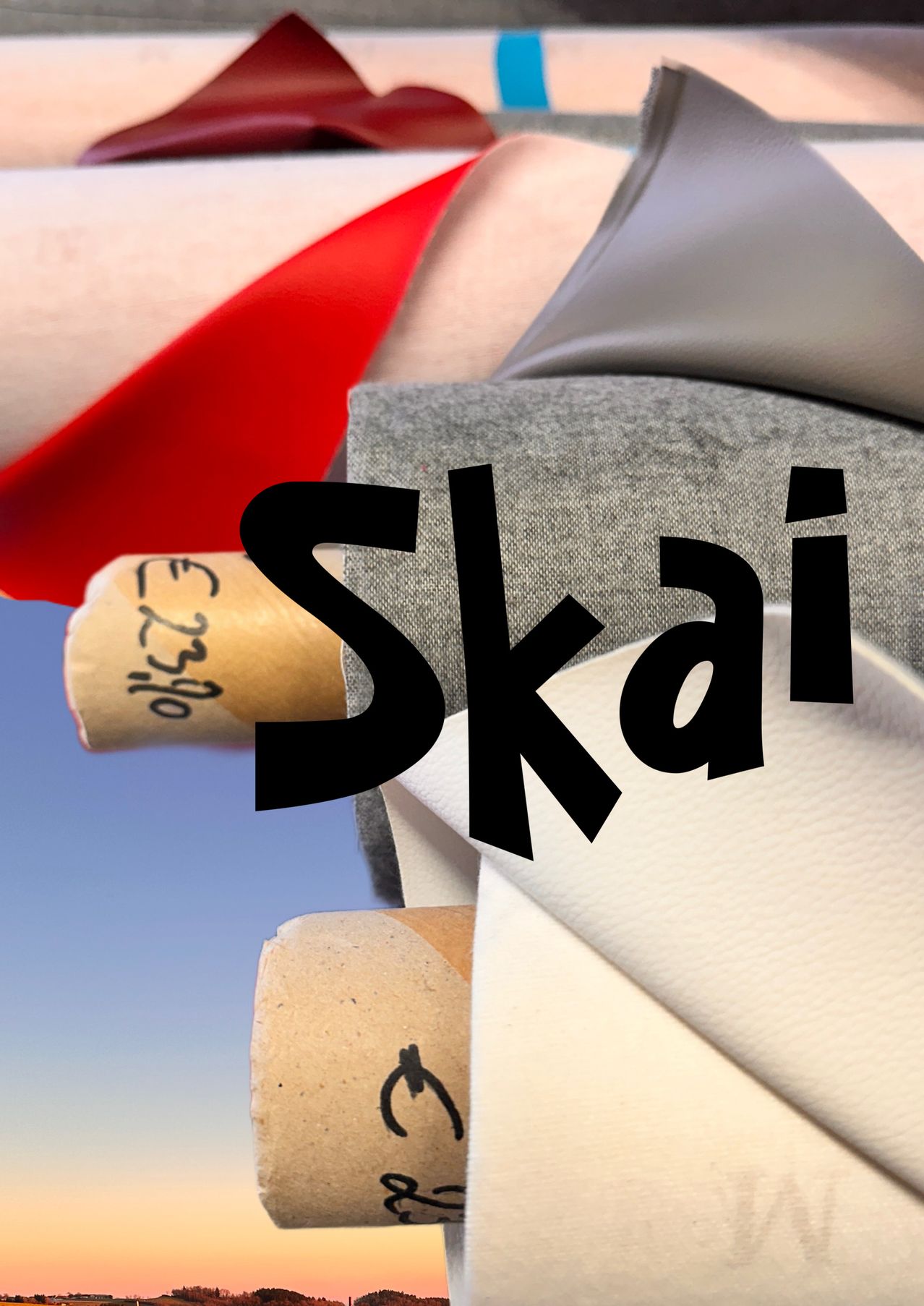 Ein Nahaufnahme eines Holzkorkens mit der Nummer 2349. Er liegt auf einem grauen Stoff, mit dem Wort 'Skai' in fetten schwarzen Buchstaben. Ein rotes Band und ein weißer Stoff sind ebenfalls sichtbar.