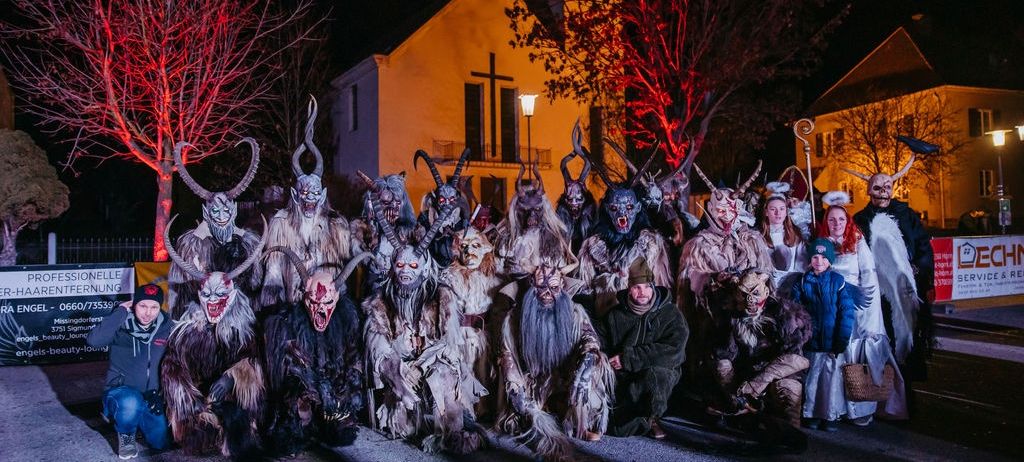 Eine Gruppe von Menschen in gruseligen Kostümen und Masken posiert nachts vor einer Kirche für ein Foto.