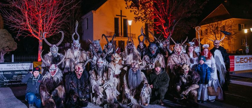 Eine Gruppe von Menschen in gruseligen Kostümen und Masken posiert nachts vor einer Kirche für ein Foto.