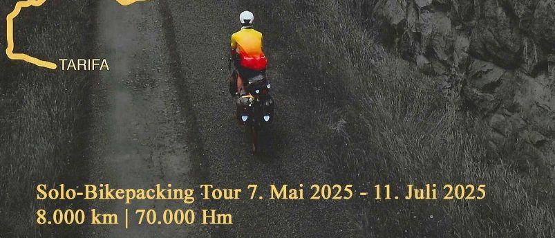 Ein Radfahrer fährt auf einem felsigen Pfad zwischen zwei großen Felswänden mit einer gelben Linie. Der Weg führt nach Tarifa, und das Wort 'Nordkap' steht in der oberen linken Ecke. Der Himmel ist bewölkt.