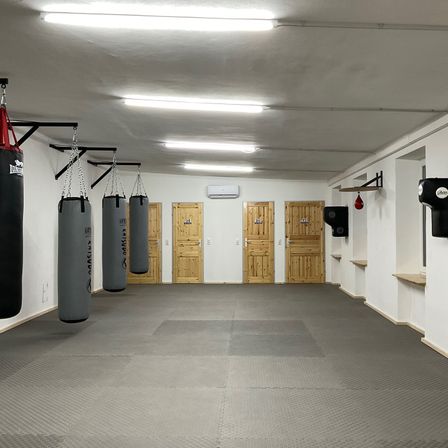 Ein leerer Raum mit Boxsäcken, die an der Decke hängen, und Holztüren an der Wand.