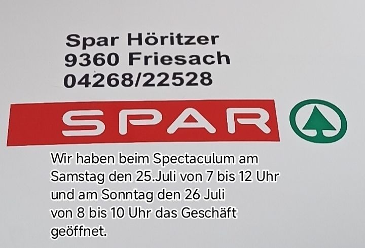 Ein weißes Schild mit schwarzem Text und einem roten Logo. Es steht 'Spar Horitzer 9360 Friesach 04268/22528' und darunter in kleinerem Text 'Wir haben beim Spectaculum am Samstag den 25.Juli von 7 bis 12 Uhr und am Sonntag den 26 Juli von 8 bis 10 Uhr das Geschaft geoffnet.'