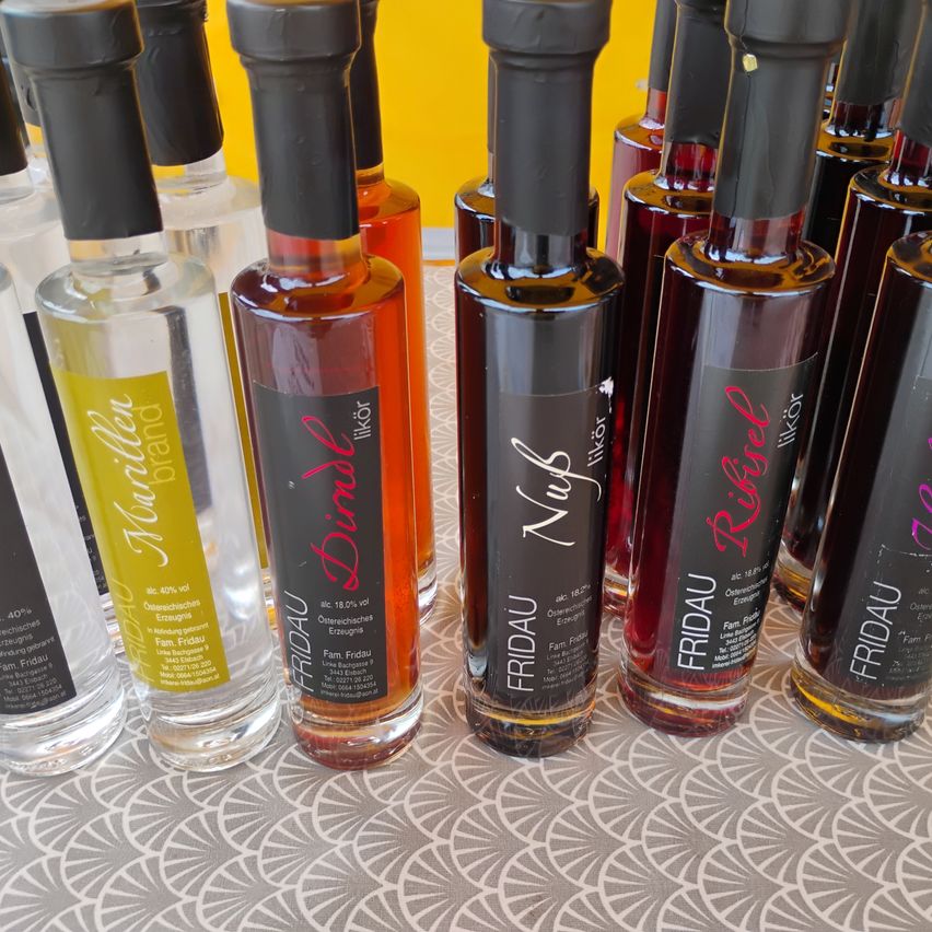 A collection of small bottles with dark labels, including names like 'Nuk' and 'Rebel', displayed on a patterned surface.