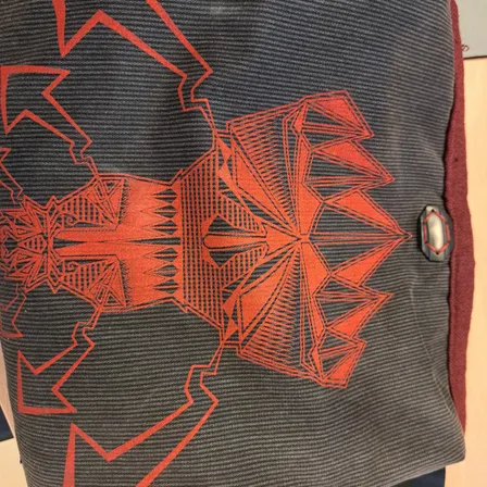 Eine schwarze Tasche mit einem roten geometrischen Muster darauf.