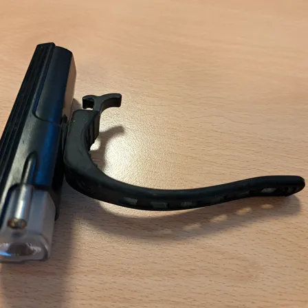 Eine schwarze Taschenlampe liegt auf einem Holztisch.