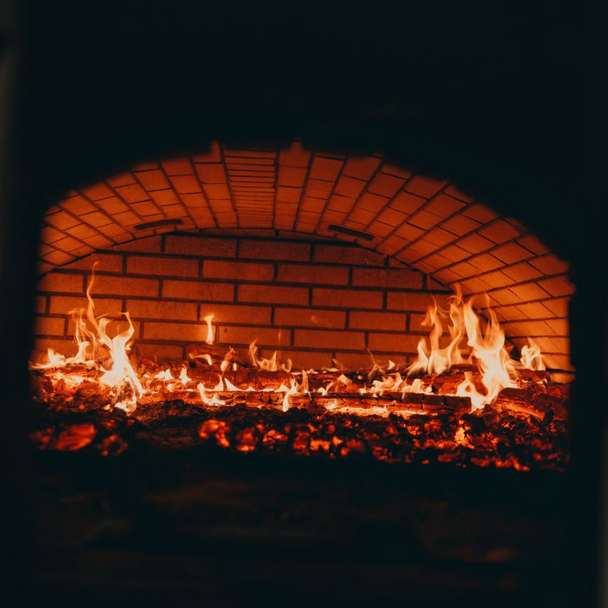 Ein feuriges Loch mit hell brennenden Flammen in einem Backofen aus Ziegeln, das warme Licht ausstrahlt.
